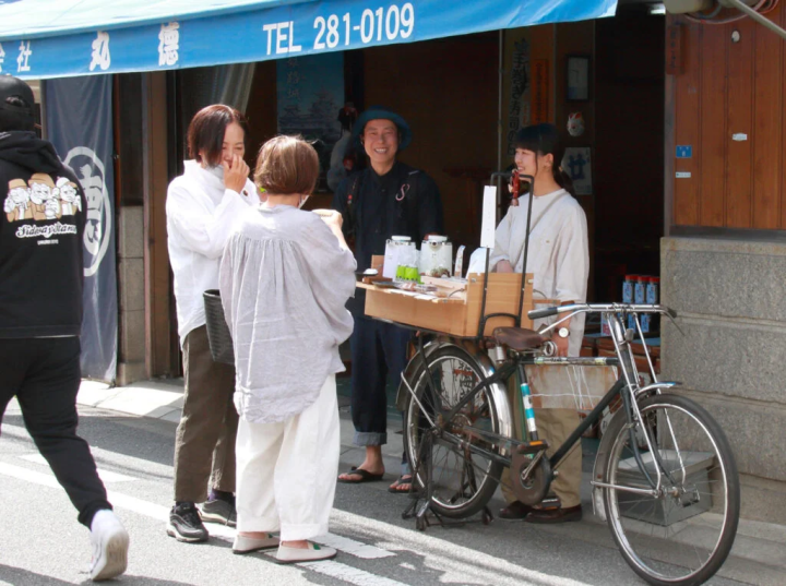 この日お披露目となった「イチバイク」。荷台の什器にチャイなどを載せて移動販売する〈ヒュッティ―〉(右)と、什器製作者の〈木犀〉(中央奥)