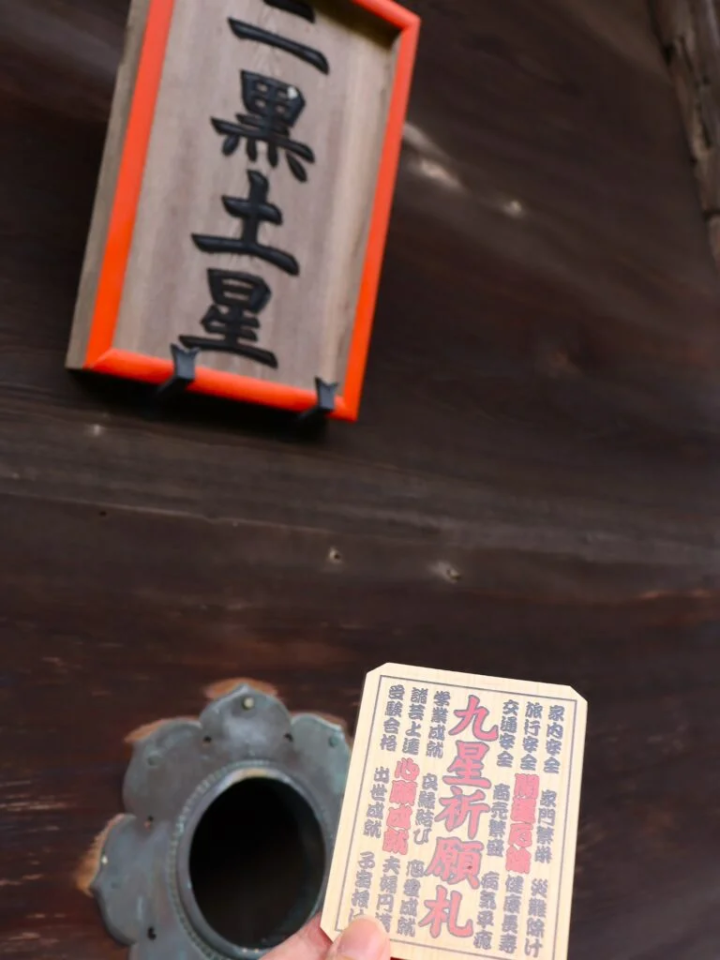 将九星祈愿牌与供养钱一起扔进洞里。 