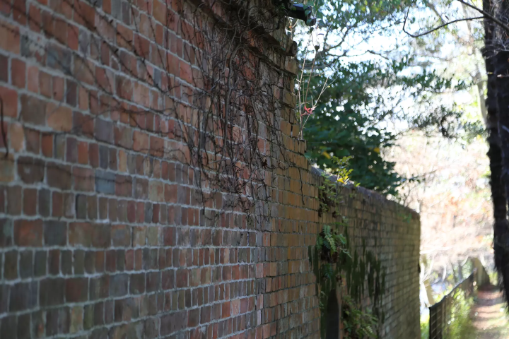 모토 씨 정원과 흐르는 수로와의 경계에있는 벽돌 벽 