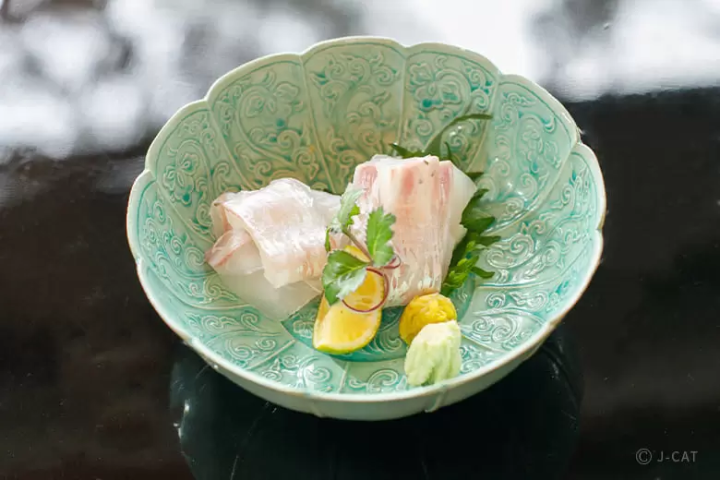 raw fish in a bowl with lemon slices