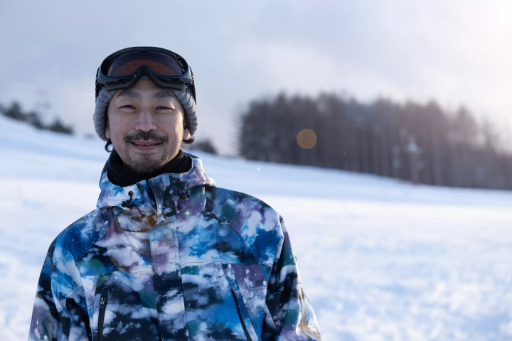 asian man smiling wearing snowboarding gear