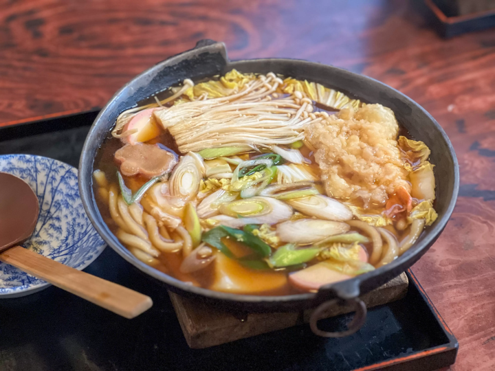 "Okanemochi" is a hearty miso stewed udon noodle dish with over 10 ingredients, including shrimp tempura, eggs, and mochi.