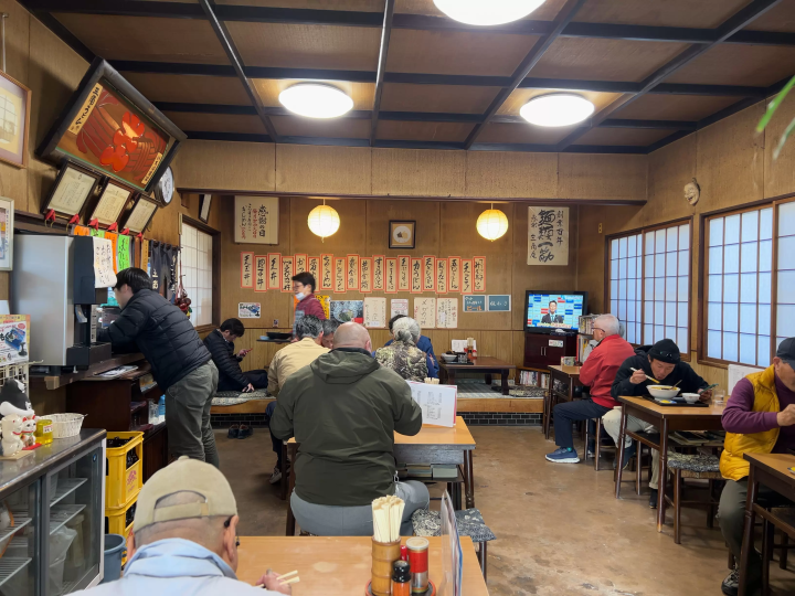 The shop is bustling with customers and has an old-fashioned atmosphere.