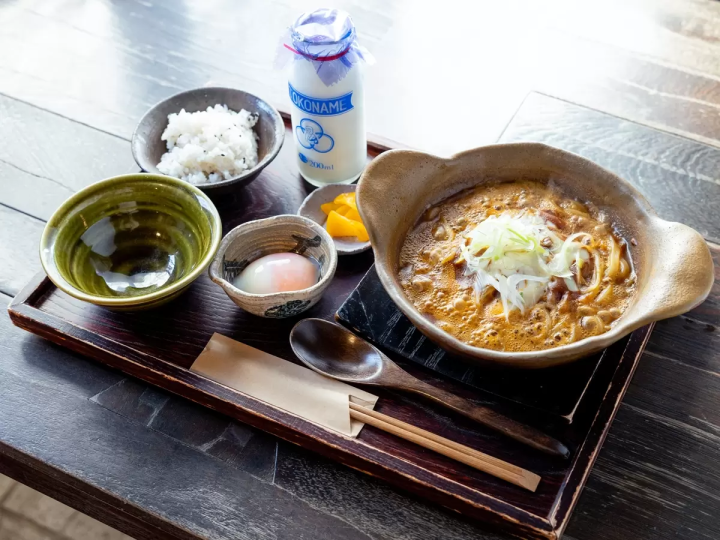 A set meal featuring curry in an earthenware pot, a soft-boiled egg, and rice, plus Tokoname milk! 